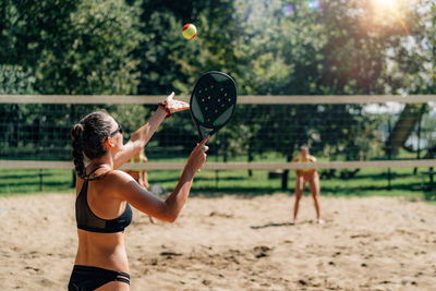 Female friends playing beach tennis