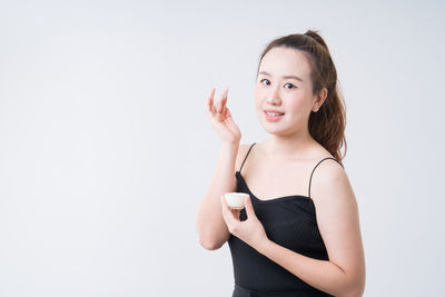 Portrait of smiling young woman against white background