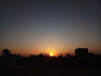 Silhouette cityscape against clear sky during sunset