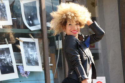 Smiling woman with curly hair standing in city on sunny day