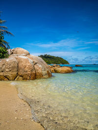 Rocks on beach against blue sky