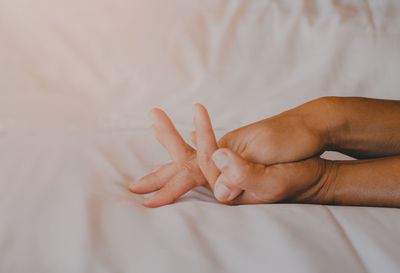 Close-up of person hand on bed