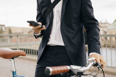 Midsection of man holding mobile phone