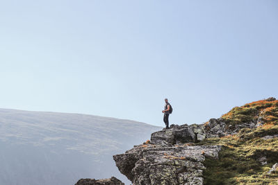 Man standing on rock against clear sky