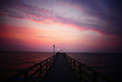 Pier over sea against sky during sunset