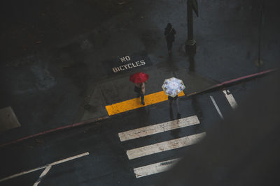 High angle view of people walking on street during rain