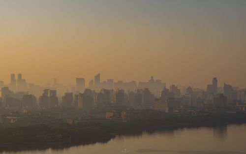 Buildings in city against clear sky during sunset