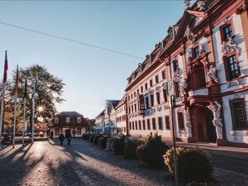 Road by buildings against clear sky