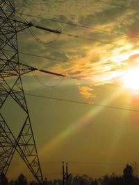 Low angle view of electricity pylon at sunset