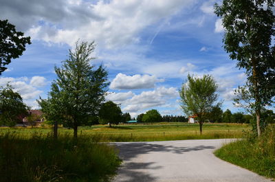 Scenic view of green field and road against sky