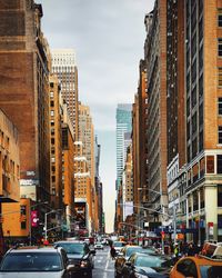 Traffic on road amidst buildings in city against sky