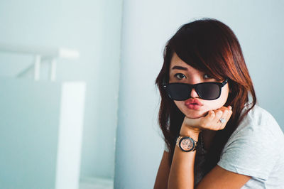 Portrait of woman wearing sunglasses against wall