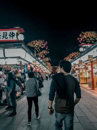 Rear view of people walking on street at night