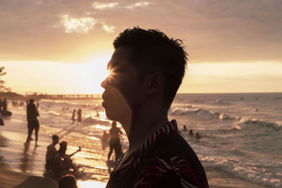 Portrait of man on beach against sky during sunset