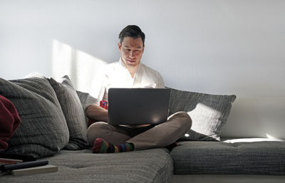 Man using laptop while sitting on sofa at home