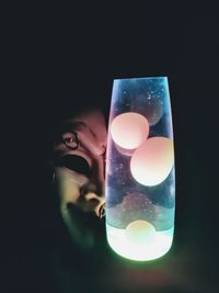 Close-up of woman holding glass against black background