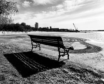 Empty bench in park against sky