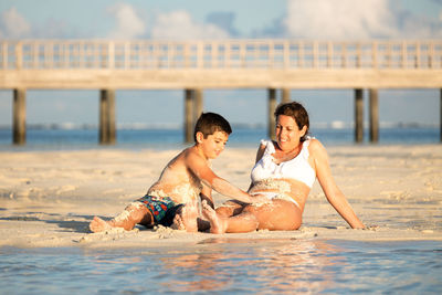 Mother and son covering each other in mud on the beach
