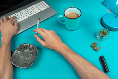 High angle view of hand holding coffee cup on table