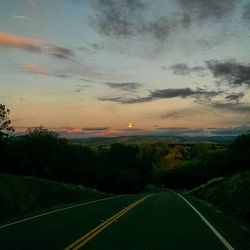 Country road against cloudy sky at sunset