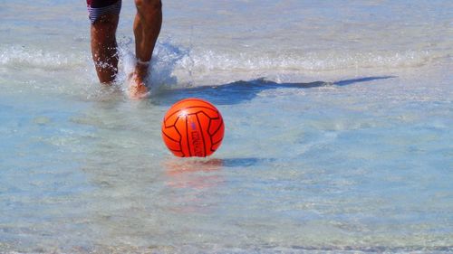 Midsection of man playing with ball in water at beach