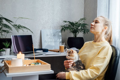 Mental health and work. work life balance. young woman with cat lighting candles, relaxing and