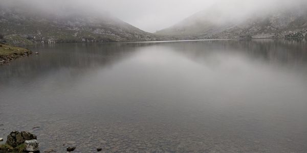 Scenic view of lake by mountains against sky