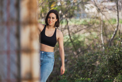 Portrait of young woman standing against trees