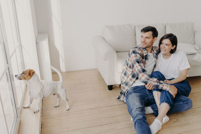 Young couple sitting on hardwood floor