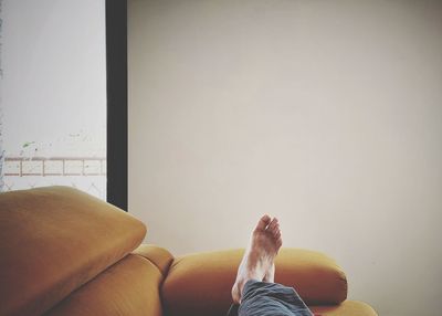 Low section of man relaxing on sofa at home