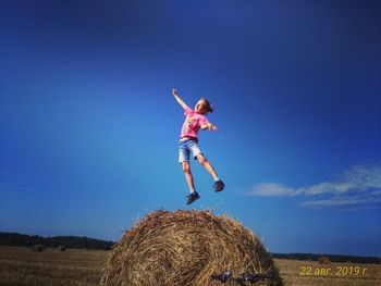 Full length of woman jumping on field against sky