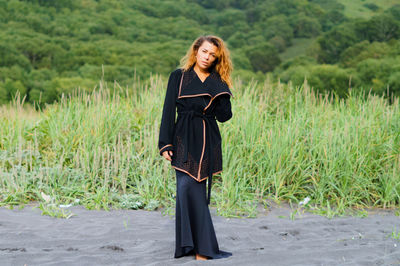 Portrait of mid adult woman wearing black dress at beach