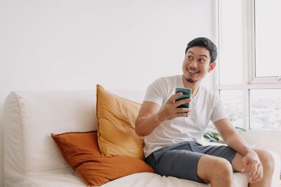 Portrait of young woman using mobile phone while lying on bed at home