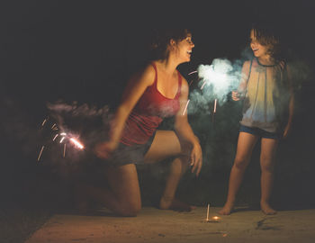 Happy mother and son with sparklers in dark