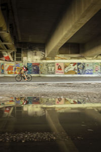 Man riding bicycle on bridge in city