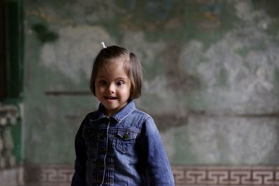 Portrait of cute girl standing in front of wall