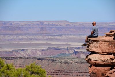 Man standing on rock against sky