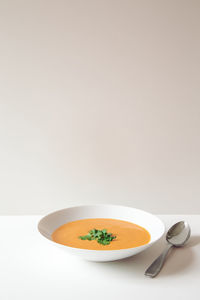 Creamy bright orange soup in front of light background