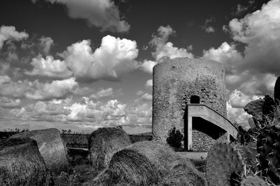 Hay bales by castle against sky