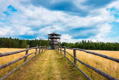 Wooden lookout tower in zwierzyniec. the path leading to the hill is fenced off with a wooden fence