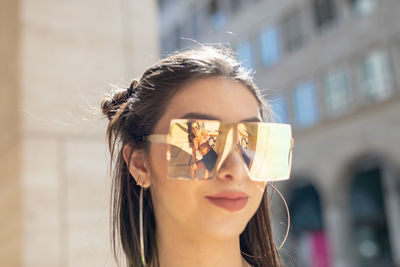 Young woman wearing sunglasses with reflection of friend