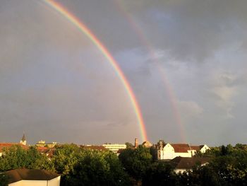 Rainbow over city against sky