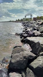 View of rocks in sea against cloudy sky