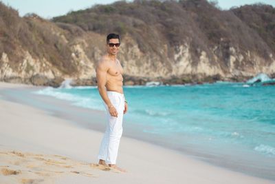 Portrait of shirtless man standing on beach