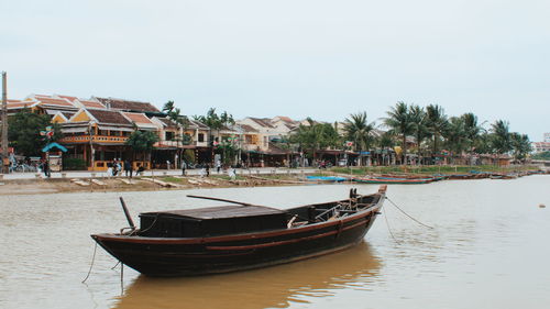 Boat moored in canal by building against sky