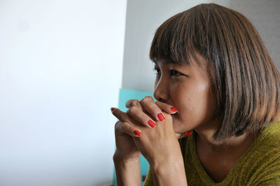 Close-up of thoughtful woman against wall