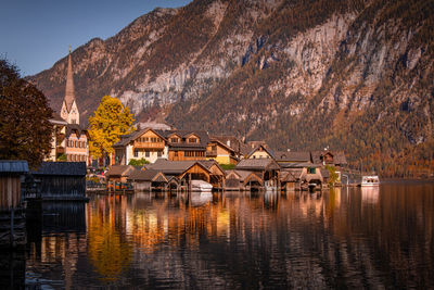 Houses by lake and buildings against sky