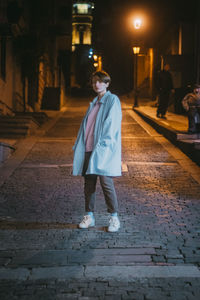 Man walking on footpath by street at night