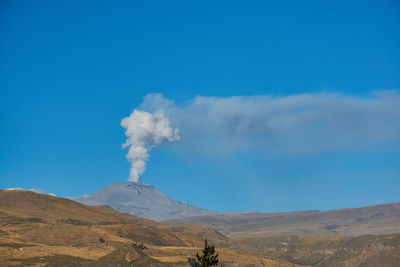 Smoke emitting from volcanic mountain against sky