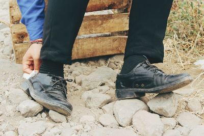 Low section of man cleaning shoe with tissue paper on rocks